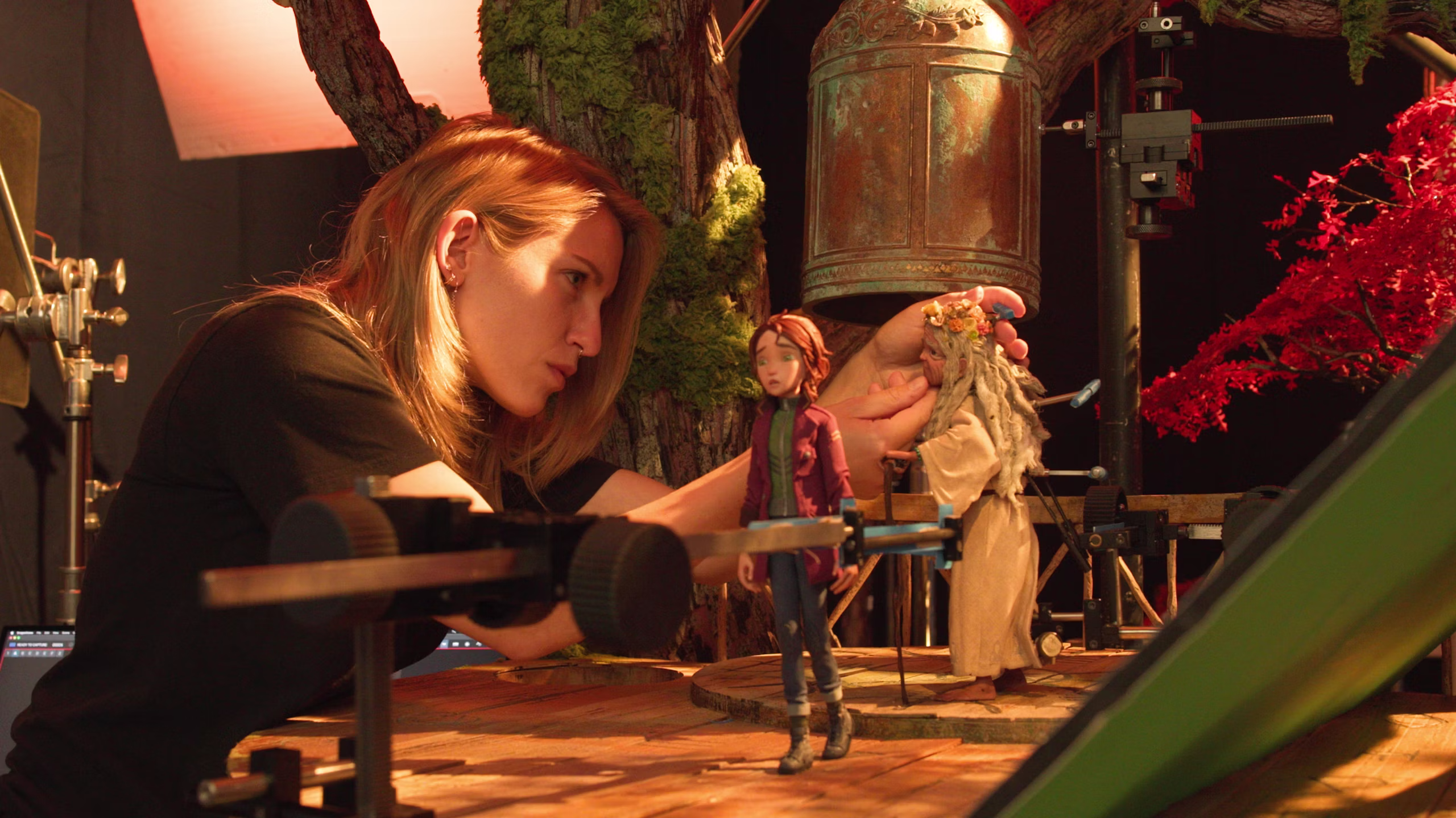 La imagen muestra a una animadora de Laika Studios en pleno set de filmación manipulando, manualmente, a las marionetas de Prue y la anciana del bosque Ifigenia. Al fondo se ve parte de la escenografía y algunas herramientas de apoyo